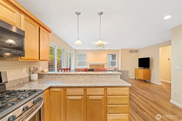 a kitchen with stainless steel appliances granite countertop a sink a stove and a wooden floor