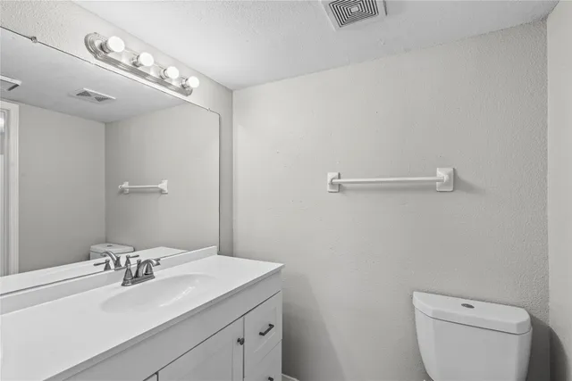 a bathroom with a sink vanity granite and toilet