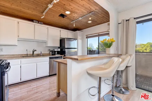 a kitchen with stainless steel appliances granite countertop a sink a stove a refrigerator cabinets and chairs