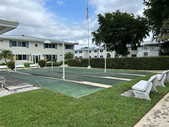 a view of a white house with a big yard and large trees