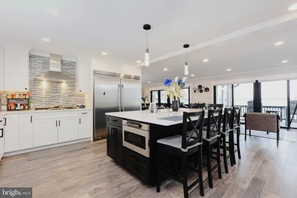 a kitchen with stainless steel appliances kitchen island granite countertop a table chairs sink and cabinets