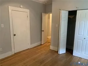 an empty room with wooden floor and closet area
