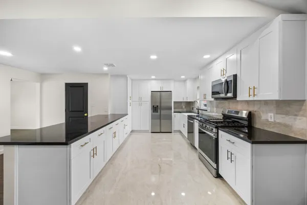 a large kitchen with stainless steel appliances kitchen island granite countertop a stove a sink and a refrigerator