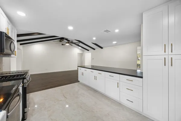 a kitchen with granite countertop white cabinets and refrigerator