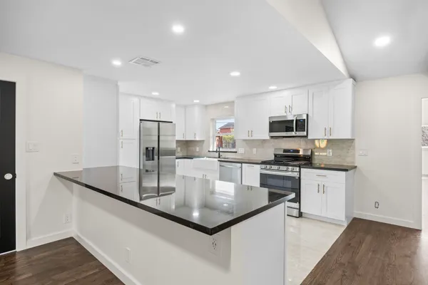 a kitchen with stainless steel appliances granite countertop a sink a stove a microwave a center island and cabinets