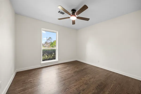 an empty room with wooden floor and ceiling fan