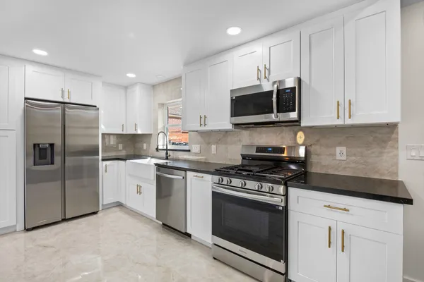 a kitchen with stainless steel appliances granite countertop a stove a refrigerator and a microwave