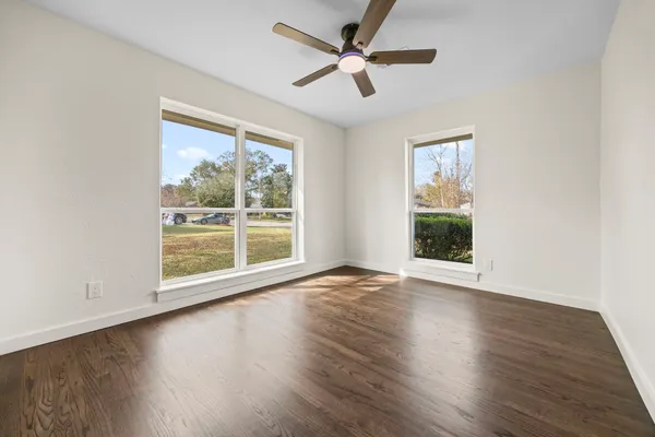 a view of an empty room with wooden floor and a window