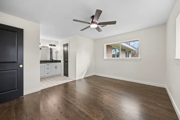 a view of empty room with wooden floor and ceiling fan
