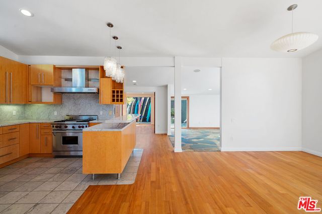 a kitchen with stainless steel appliances granite countertop a stove top oven a sink dishwasher and a refrigerator with wooden floor