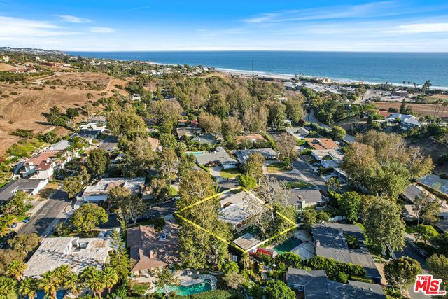 an aerial view of residential houses with outdoor space and ocean view