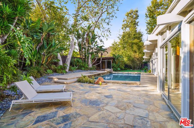 a view of backyard with swimming pool and seating space
