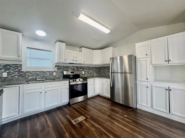 a kitchen with granite countertop a refrigerator stove top oven and sink