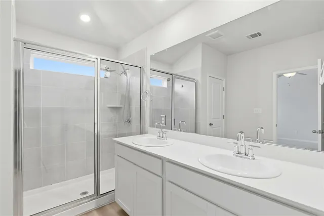 a bathroom with a double vanity sink mirror and shower