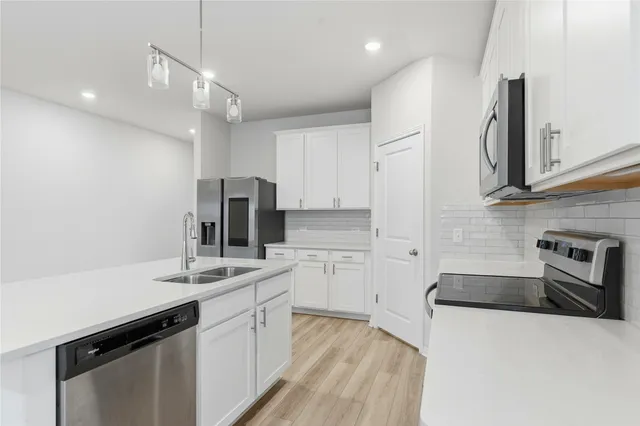 a kitchen with a sink dishwasher a stove a microwave oven and a refrigerator with wooden floor