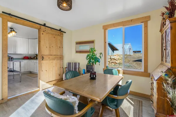 a kitchen with stainless steel appliances a sink a stove a dining table and chairs with wooden floor