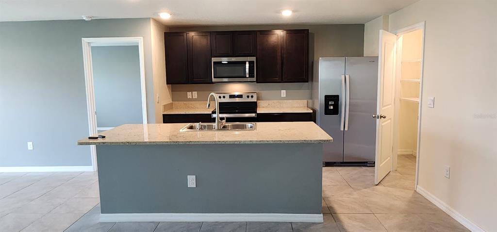 16778 Carlton Pond Street Wimauma, FL 33598 - Photo 11 of 27 a kitchen with stainless steel appliances a sink stove and refrigerator