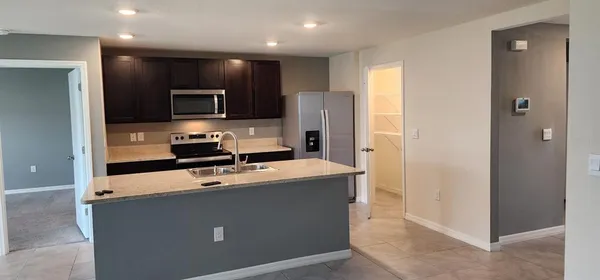 a room with stainless steel appliances a refrigerator a stove a sink and a microwave