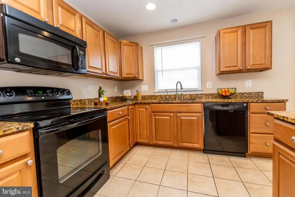 a kitchen with granite countertop a stove microwave and refrigerator