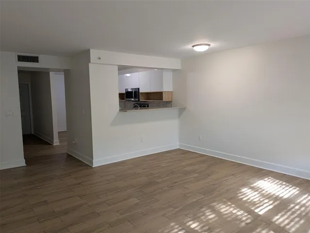a view of a room with wooden floor and a window