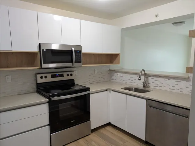 a kitchen with appliances a sink and cabinets
