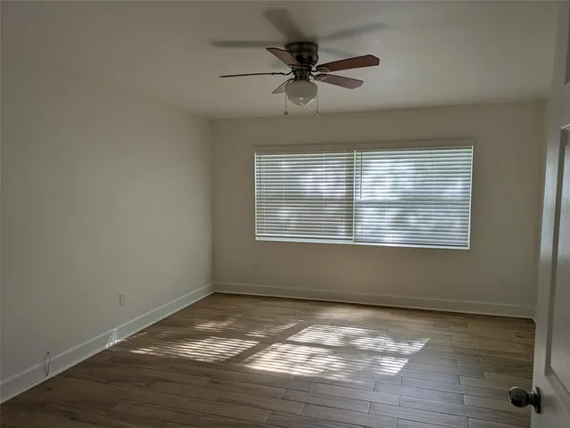a view of an empty room with wooden floor and a window
