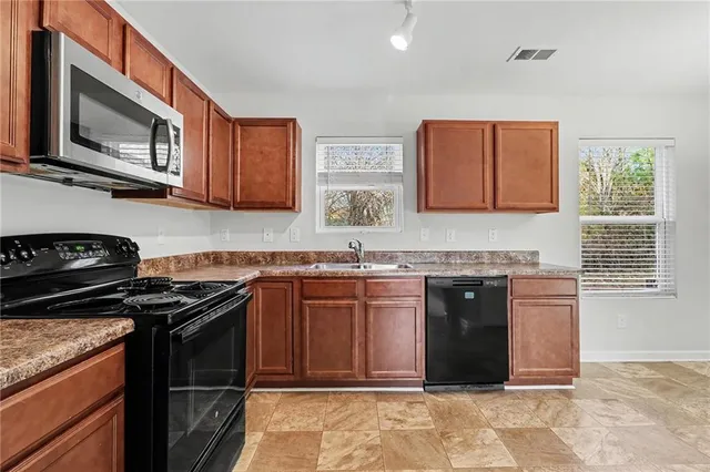 a kitchen with stainless steel appliances granite countertop a stove a sink and a microwave