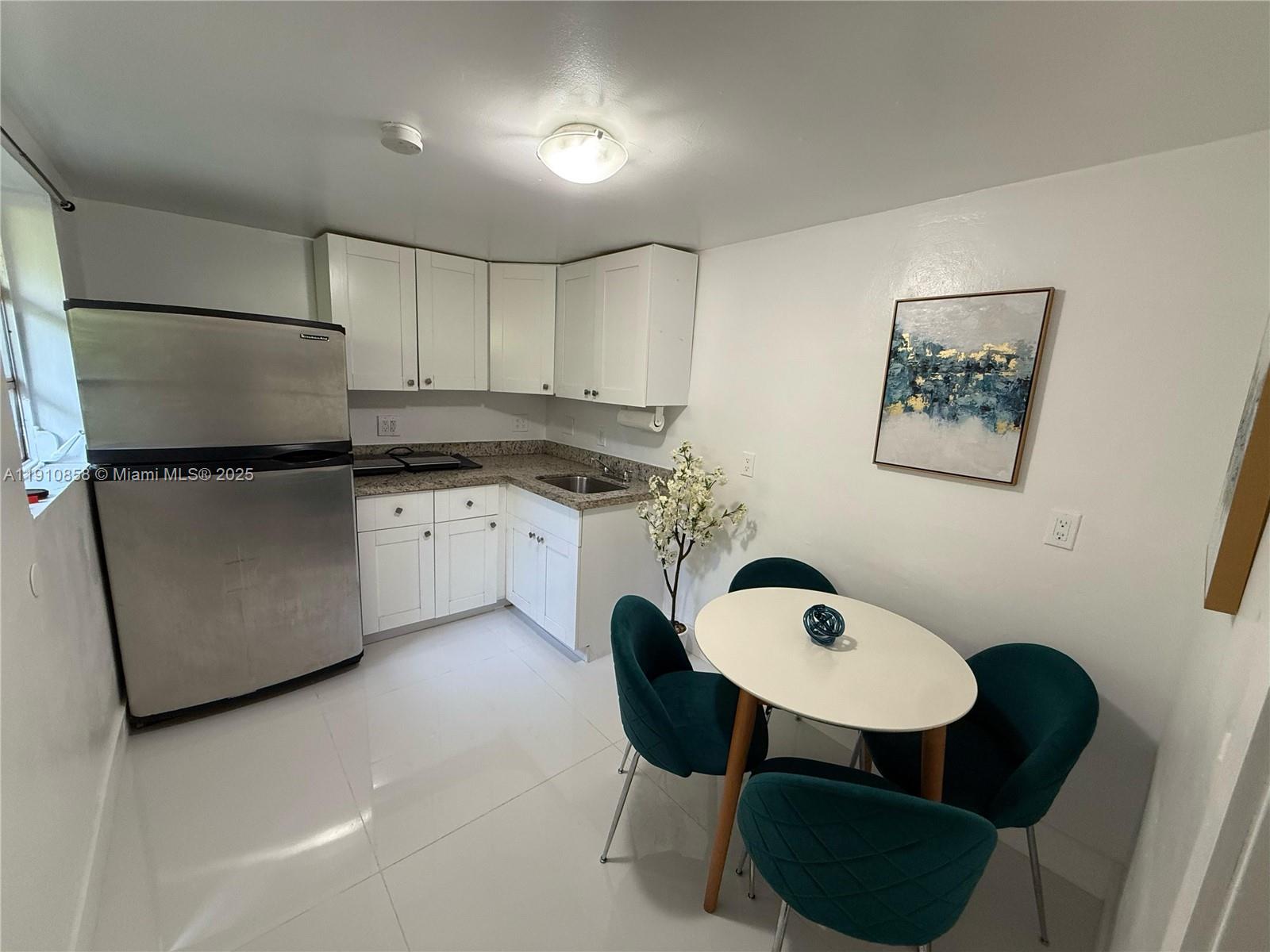 a kitchen with stainless steel appliances granite countertop a sink a stove a refrigerator with white cabinets and wooden floor