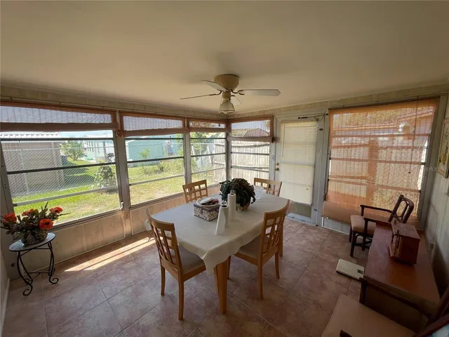 a dining room with furniture a chandelier and a large window