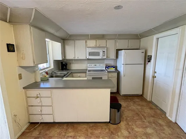 a kitchen with a refrigerator a stove top oven and white cabinets