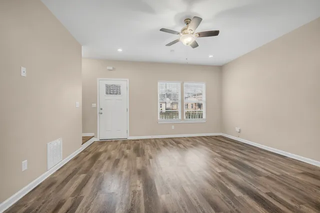 a view of an empty room with a window and wooden floor