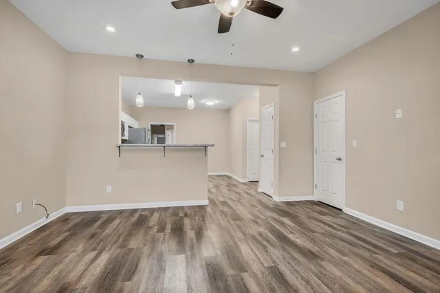 a view of kitchen and empty room with wooden floor