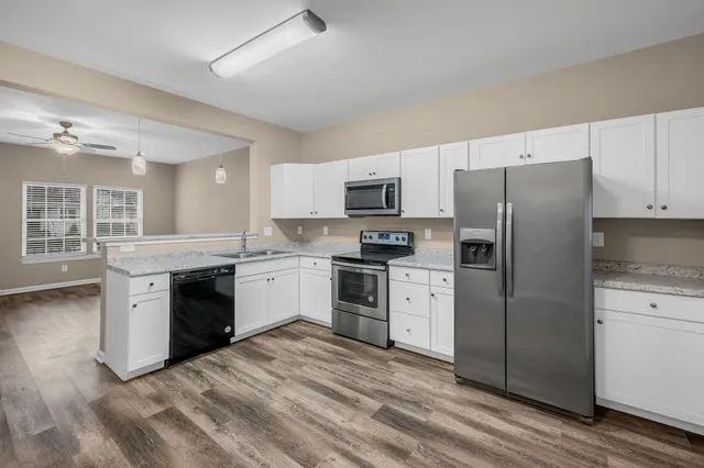 a kitchen with granite countertop a refrigerator stove and sink