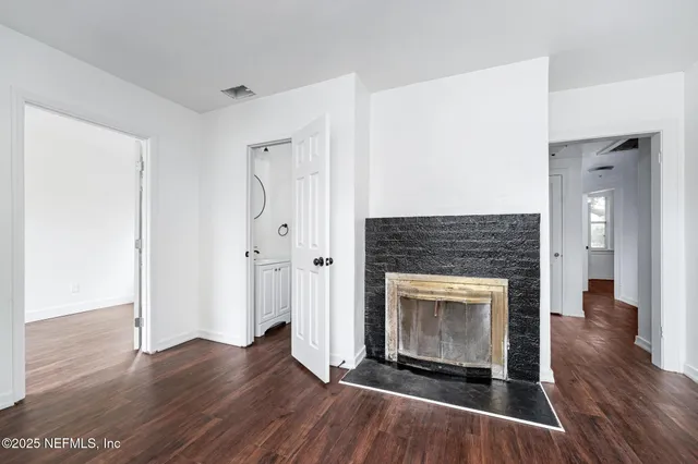 an empty room with wooden floor and fireplace