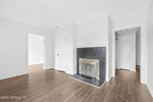 a view of empty room with wooden floor and fireplace