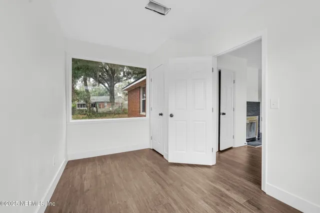 an empty room with wooden floor and windows