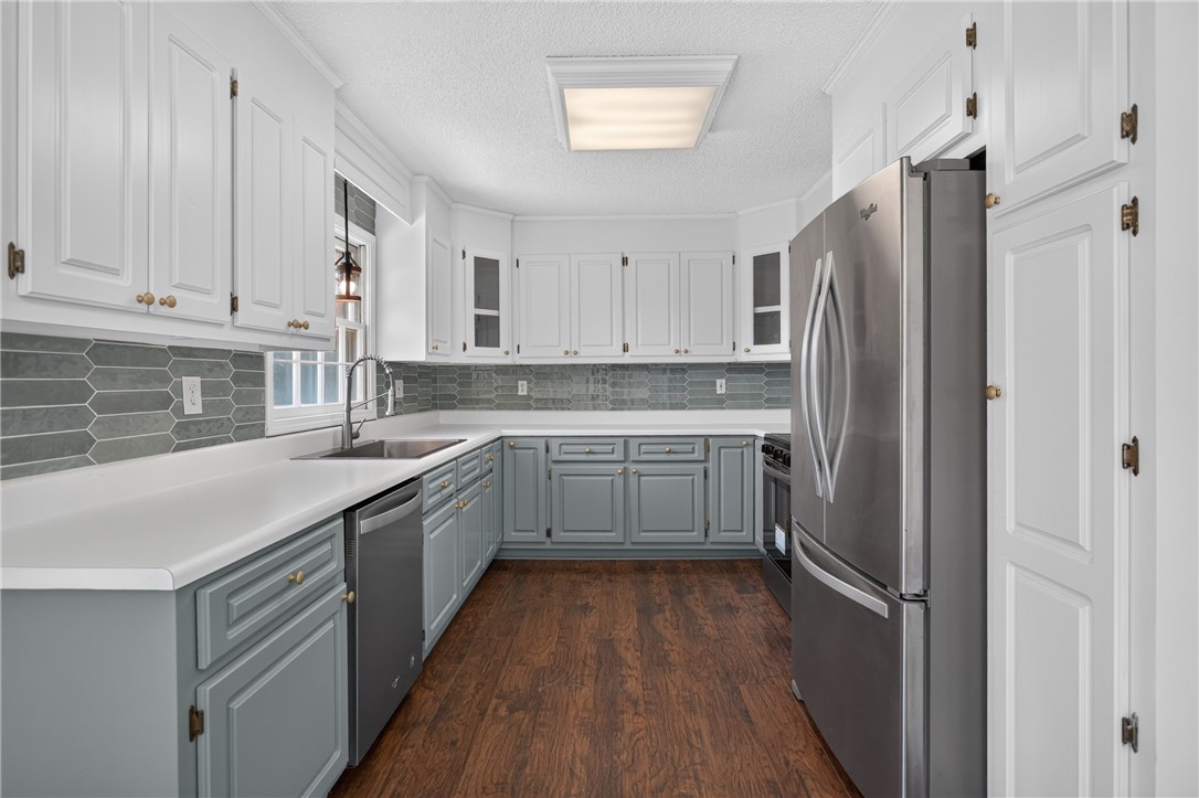 113 Greenfield Avenue Pendleton, SC 29670 - Photo 7 of 40 A contemporary kitchen showcasing rich wood flooring, sleek stainless steel appliances, and ample cabinetry for organized living.