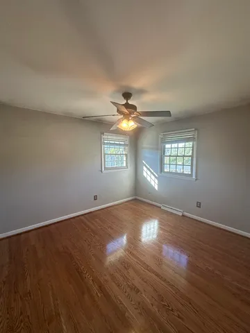 a view of an empty room with a window and wooden floor