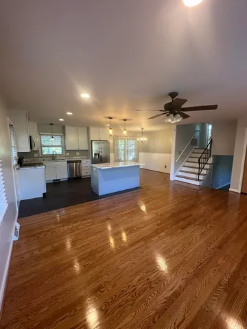 a view of kitchen and empty room with wooden floor
