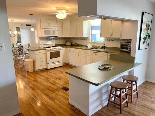 702 North Silver Circle Key Largo, FL 33037 - Photo 9 of 38 a kitchen with a table chairs a sink dishwasher stove and cabinets with wooden floor