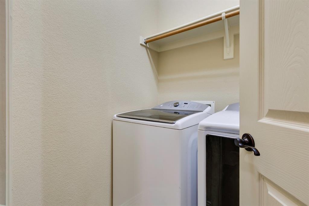 1522 Blue Jay Road Garland, TX 75043 - Photo 22 of 32 Dedicated laundry area featuring a built-in shelf and a clothes hanging rod, complemented by textured walls and a paneled door with dark hardware