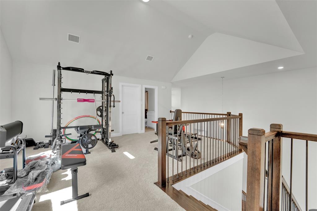 3520 Helios Lane Corinth, TX 76208 - Photo 33 of 37 Carpeted loft area featuring a vaulted ceiling, recessed lighting, and a dark wood and metal spindle railing overlooking a lower level
