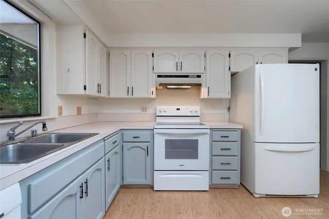 a kitchen with white cabinets and white appliances