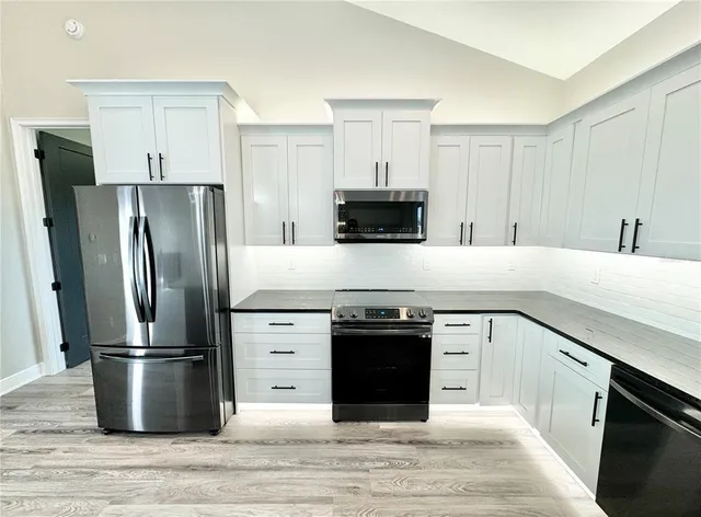 a kitchen with a stove refrigerator and microwave