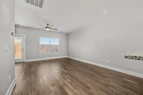 a view of a livingroom with a ceiling fan wooden floor and a ceiling fan