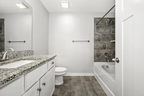 a bathroom with a granite countertop sink a toilet and a mirror