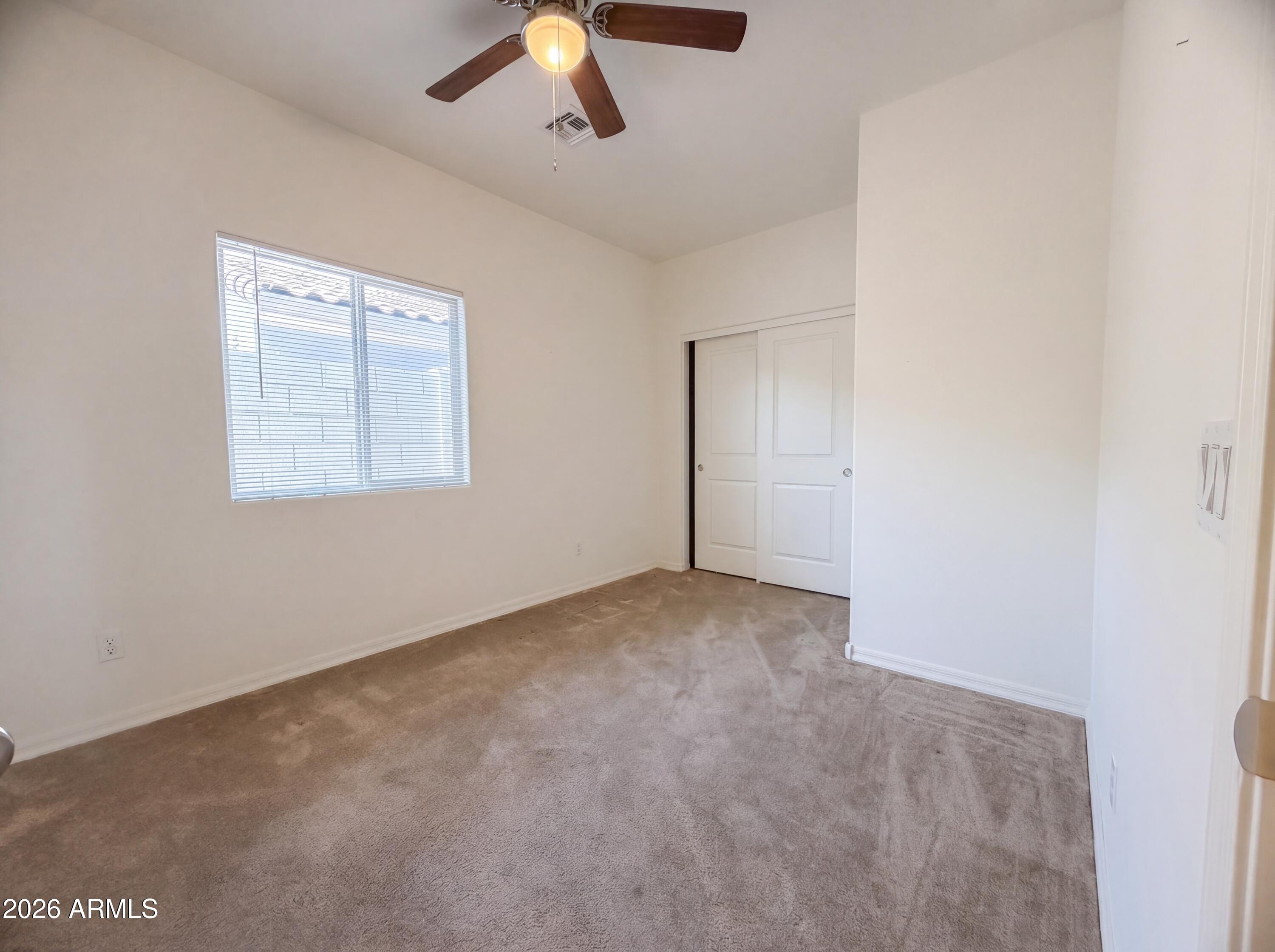 1738 South Aryelle Road Apache Junction, AZ 85119 - Photo 4 of 17 an empty room with a chandelier fan and windows