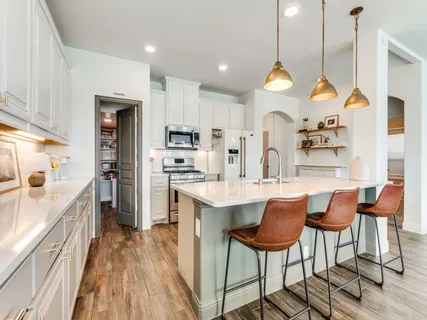 a kitchen with stainless steel appliances kitchen island granite countertop a table chairs and a refrigerator