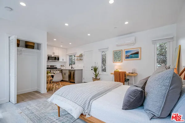 a spacious bedroom with a bed and a view of kitchen