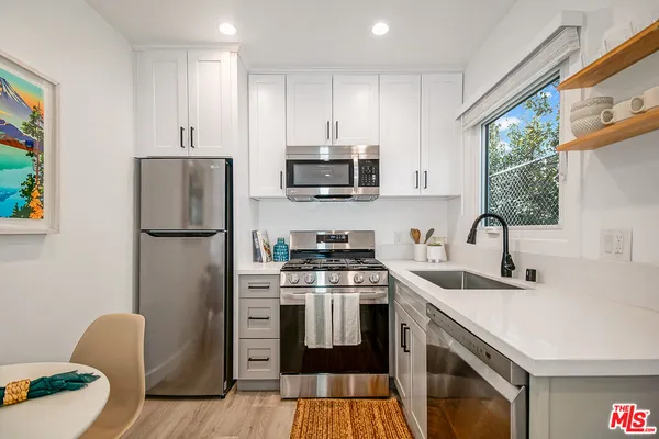 a kitchen with stainless steel appliances granite countertop a stove a sink dishwasher a refrigerator and a microwave